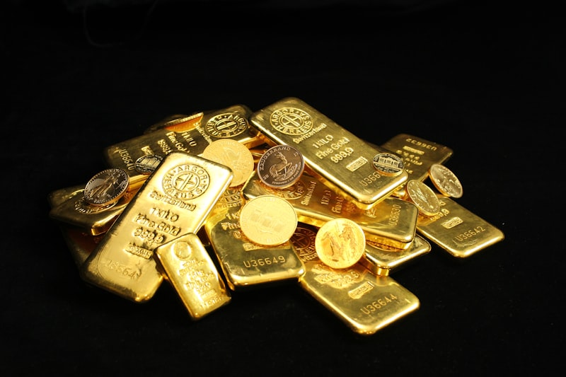 Pile of gold bullion bars and sovereign coins on a black surface